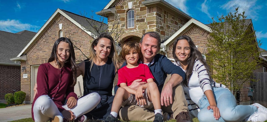 Happy family in front of new home using Colorado FHA Loans program.